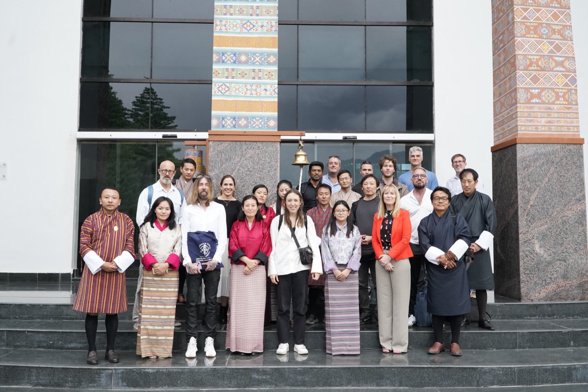 Forum scholars and hosts, many in traditional Bhutanese dress, gathered on the steps of a venue in Bhutan