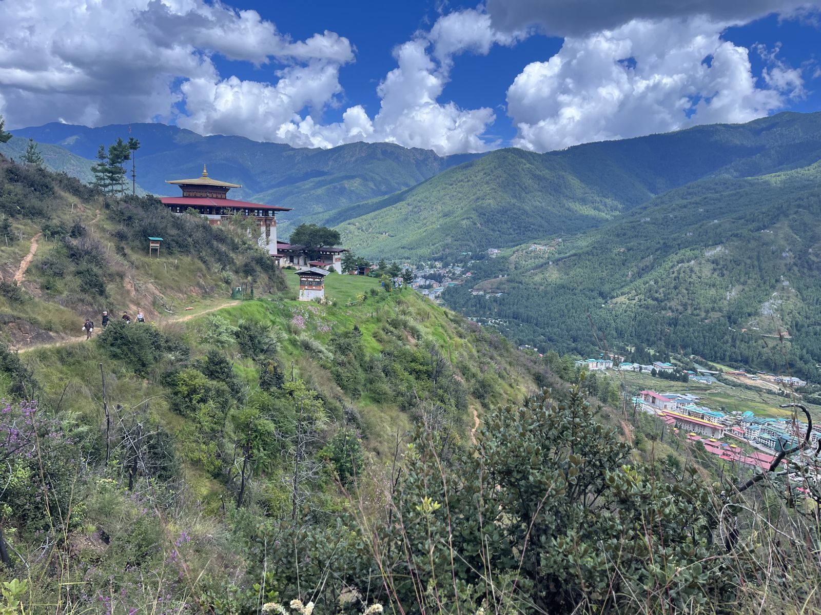 A temple on a green hillside overlooking Thimphu