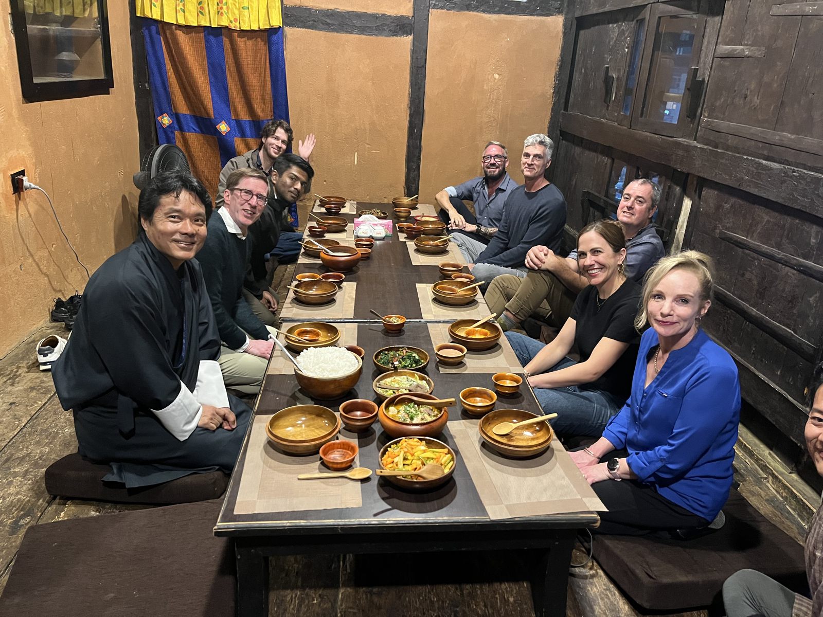 Scholars sharing a traditional Bhutanese dinner at a low wooden table