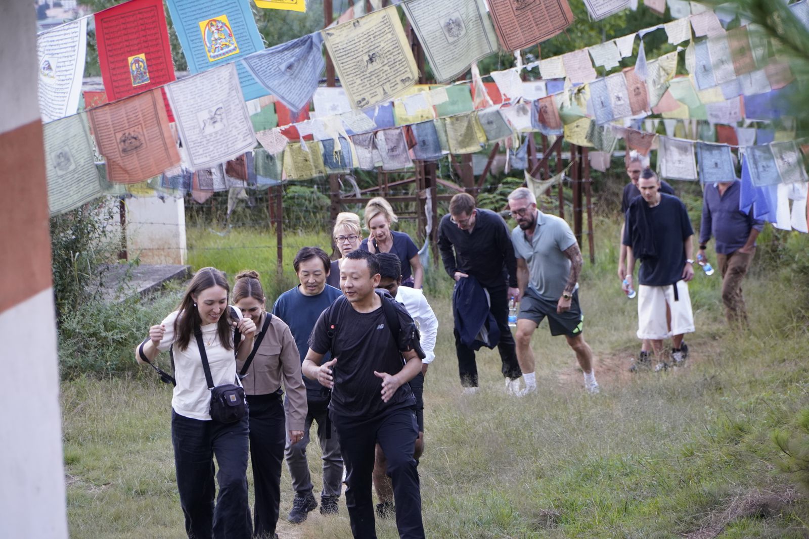 Forum scholars walking uphill past rows of prayer flags